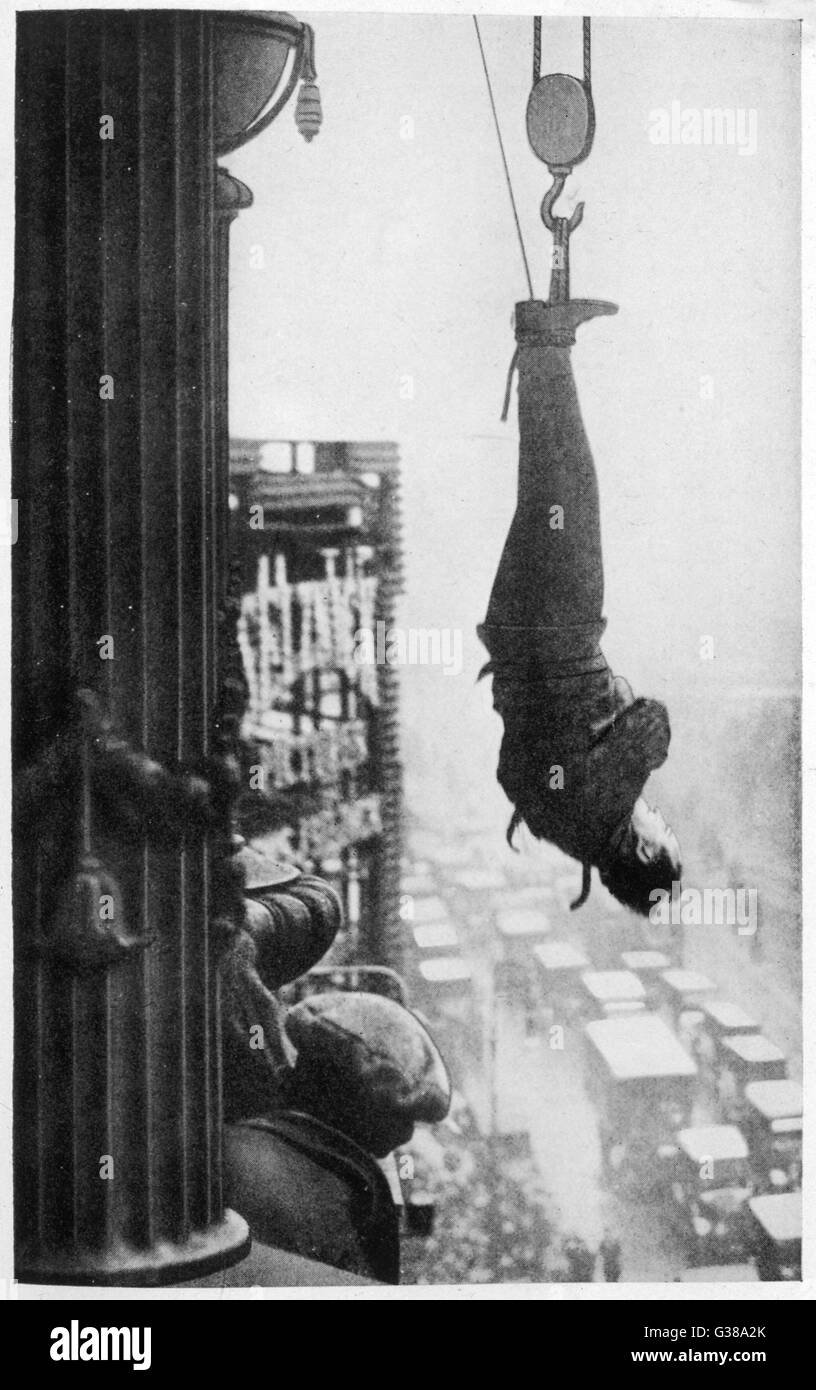Suspended from the cornice of  a New York skyscraper, he must  somehow free himself of his  chains and make his way to  safety... will he do it ? Is this one trick too many ? Stock Photo