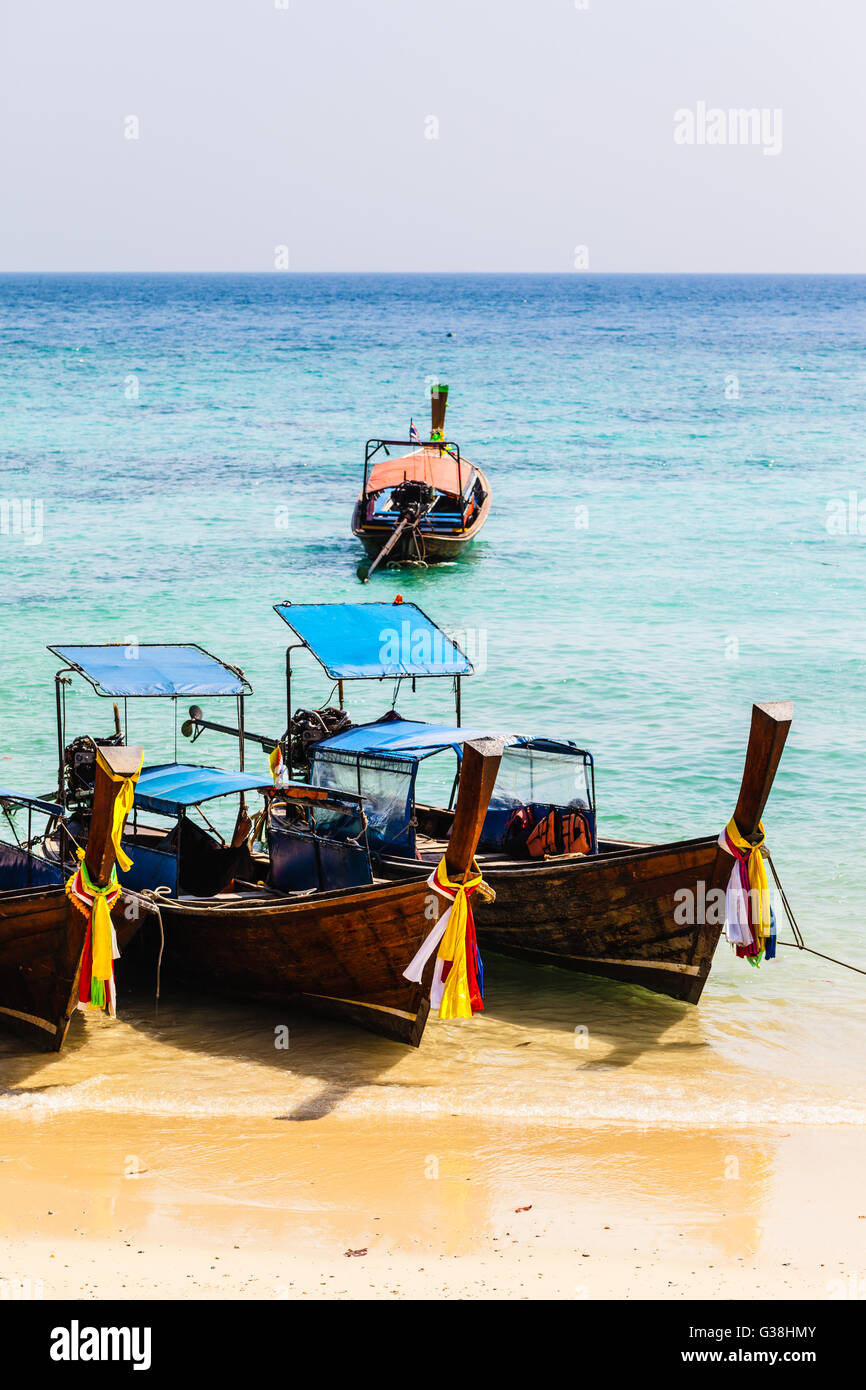 a thai traditional long tail boat in a tropical island with azure vibrant sea Stock Photo