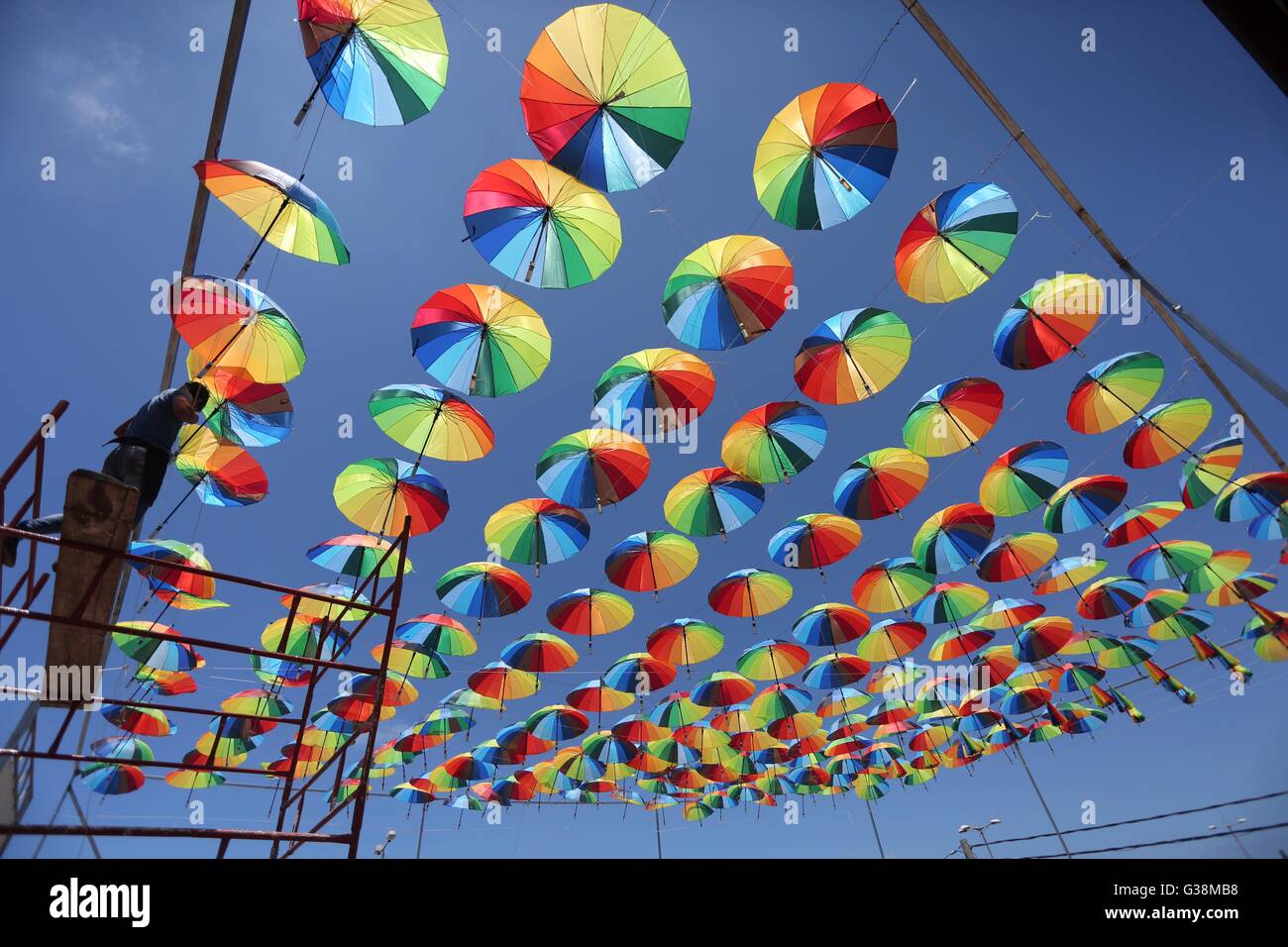 Gaza City, Gaza Strip, Palestinian Territory. 9th June, 2016. A Palestinian worker of a beachside café shop decorates its terrace with hanging colourful umbrellas as part of decorations for the Muslim holy fasting month of Ramadan in Gaza City, on June 9, 2016. Ramadan is sacred to Muslims because it is during that month that tradition says the Koran was revealed to the Prophet Mohammed. The fast is one of the five main religious obligations under Islam. More than 1. Credit:  ZUMA Press, Inc./Alamy Live News Stock Photo