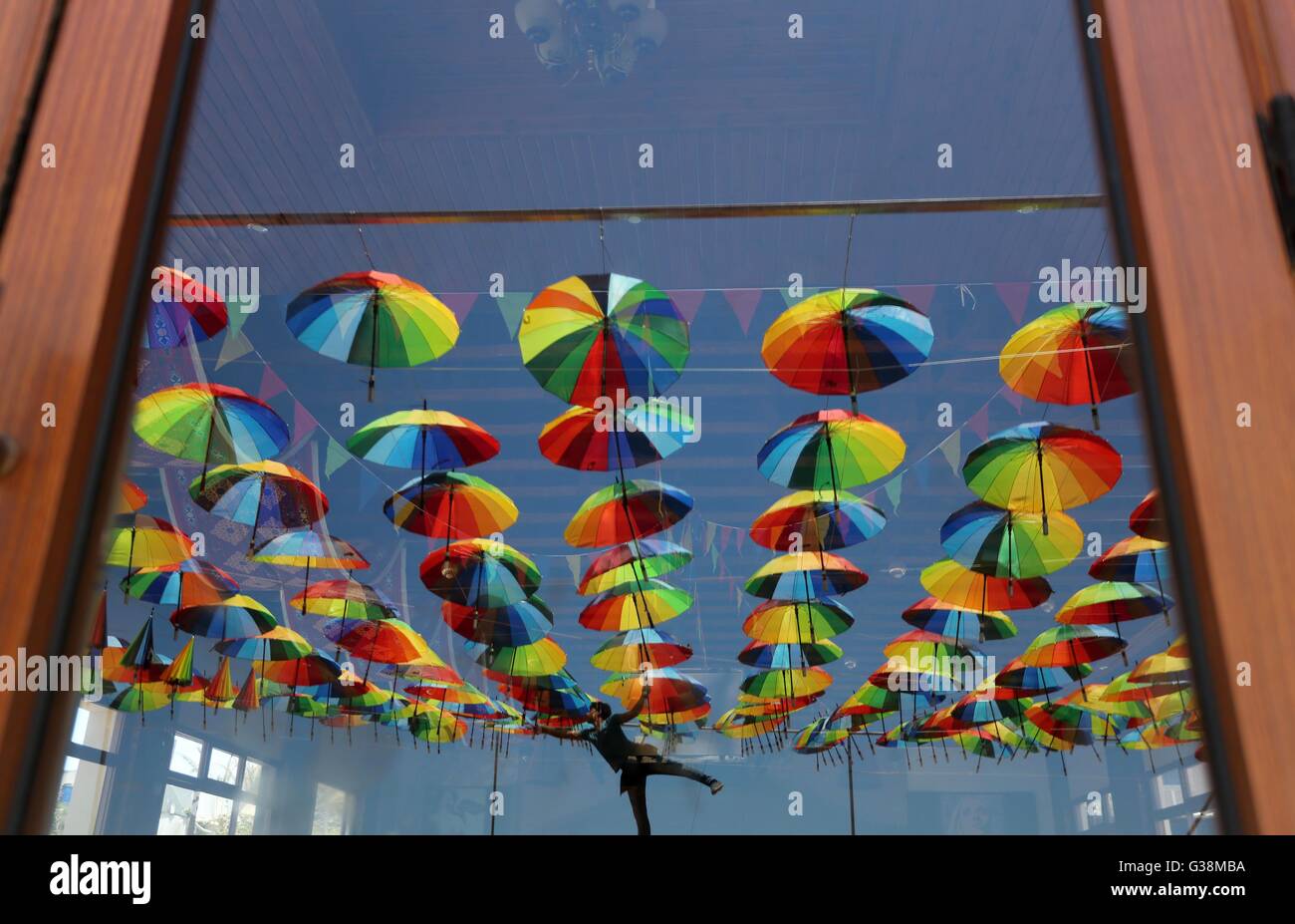 Gaza City, Gaza Strip, Palestinian Territory. 9th June, 2016. A Palestinian worker of a beachside café shop decorates its terrace with hanging colourful umbrellas as part of decorations for the Muslim holy fasting month of Ramadan in Gaza City, on June 9, 2016. Ramadan is sacred to Muslims because it is during that month that tradition says the Koran was revealed to the Prophet Mohammed. The fast is one of the five main religious obligations under Islam. More than 1. Credit:  ZUMA Press, Inc./Alamy Live News Stock Photo