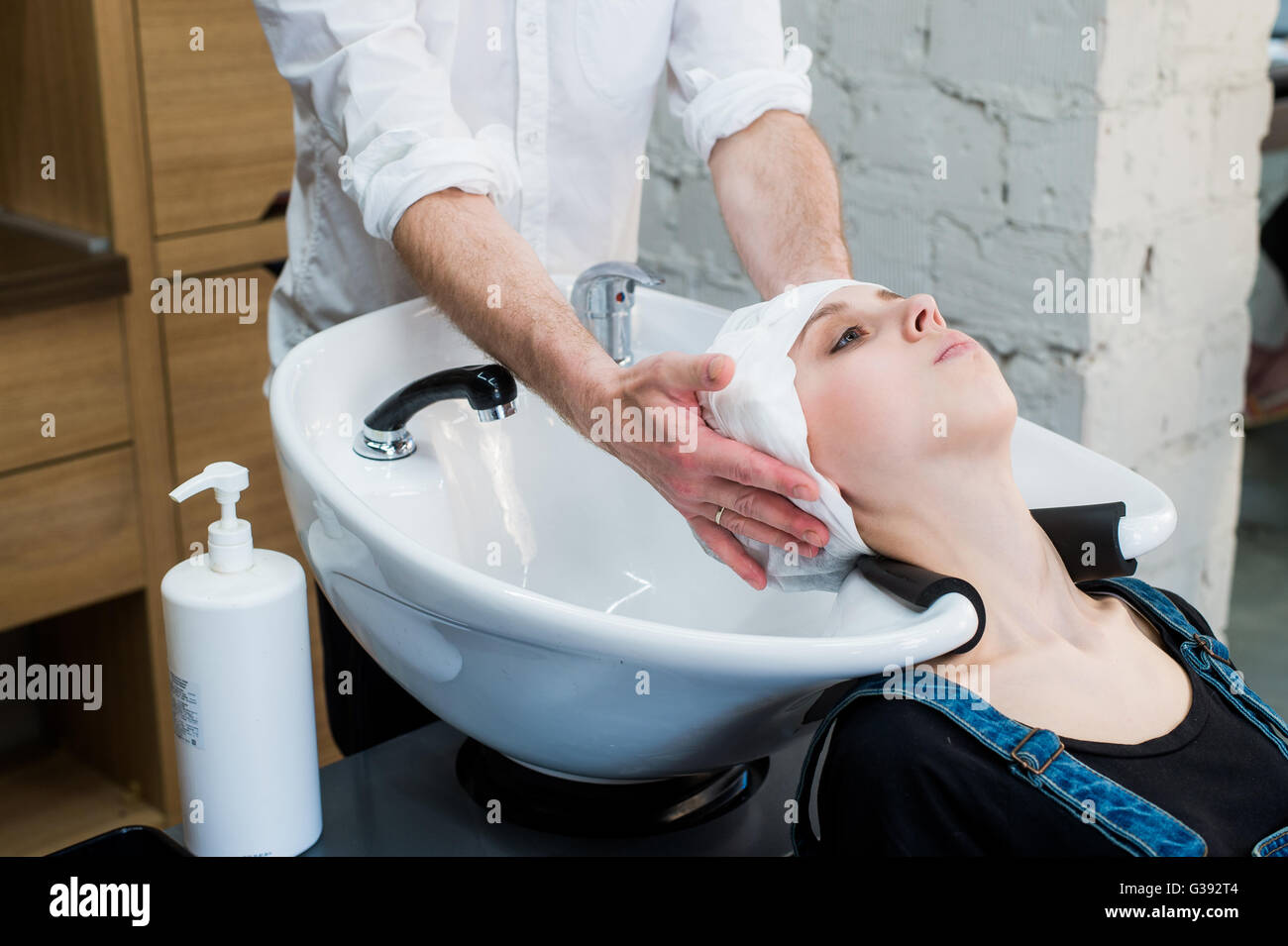 Hairstylist at work hairdresser washing hair to the customer before