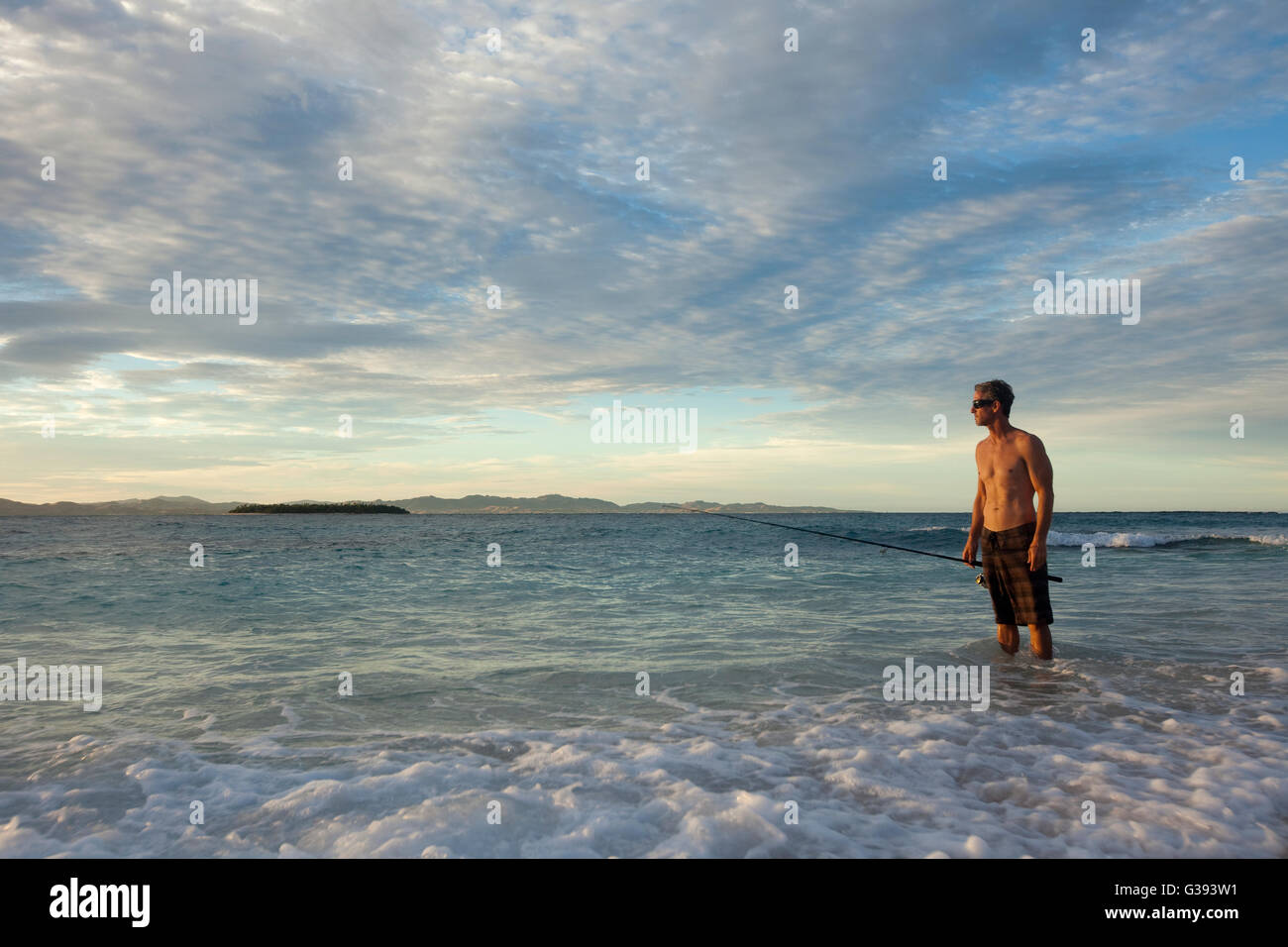 Brad Osborn fishing for Papio at sunrise on the beach at Namotu Island, Fiji Stock Photo