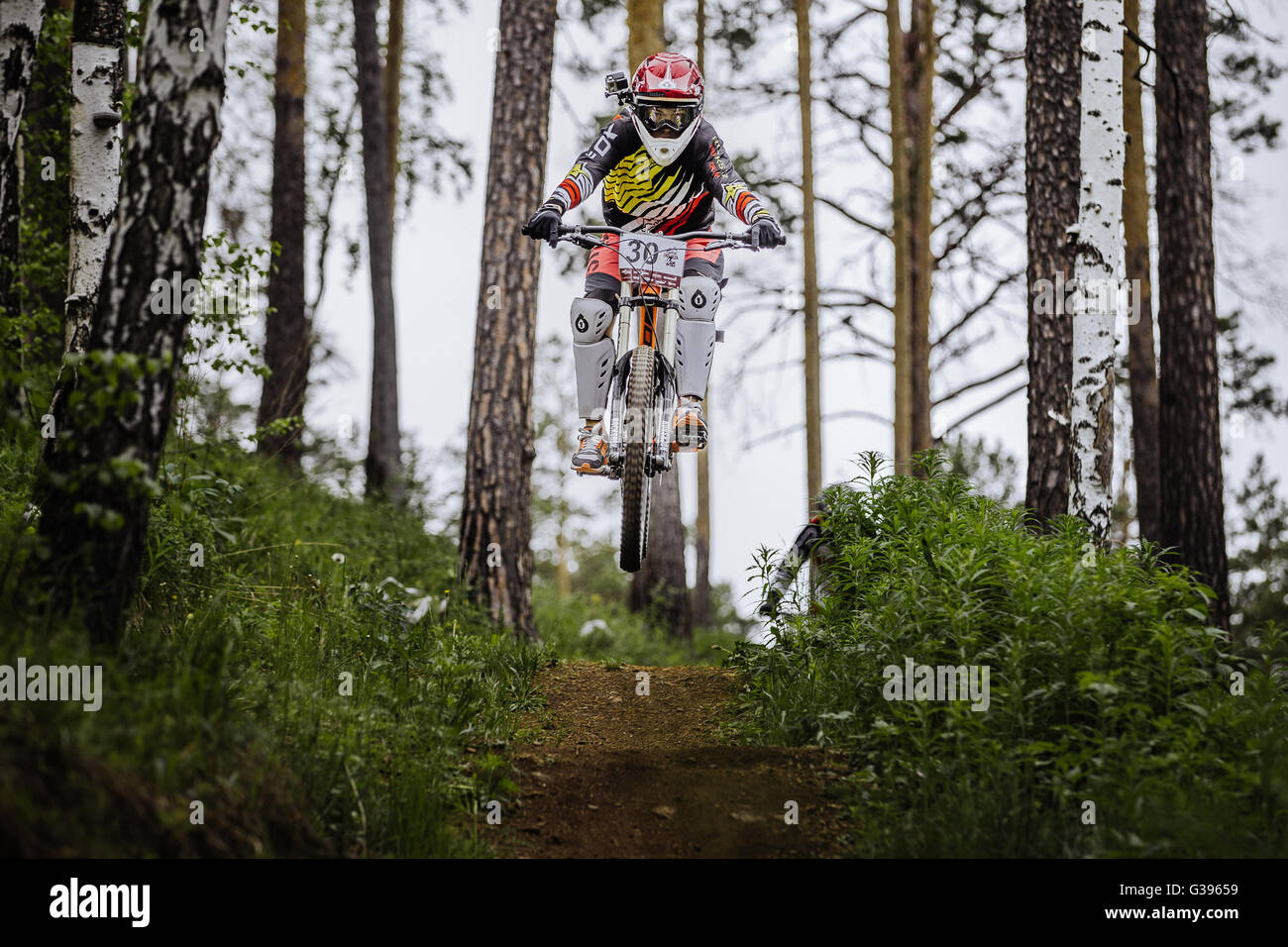 athlete racer bike jump with a mountain in forest on helmet video camera during Cup 'Ryder' downhill Stock Photo