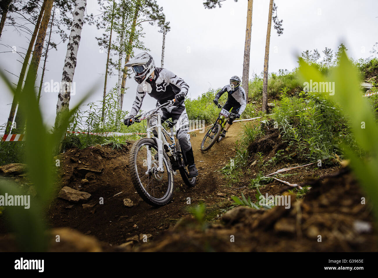 two riders of athlete on bike down through woods from mountain during Cup 'Ryder' downhill Stock Photo