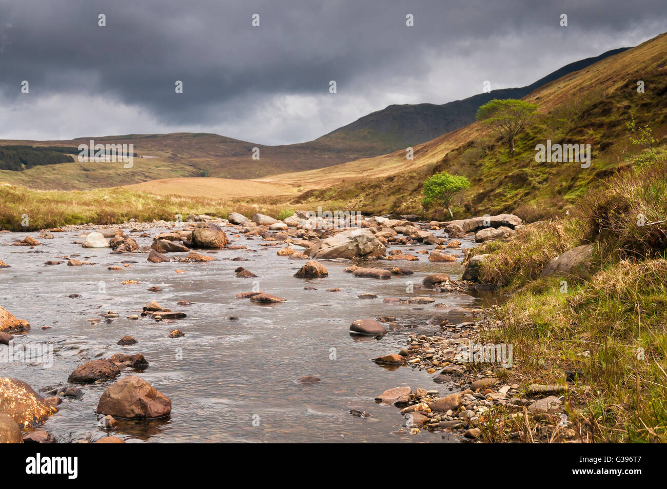 A photograph looking up stream along the River Brittle with a threatening sky, on the Isle of Skye in Scotland. Stock Photo