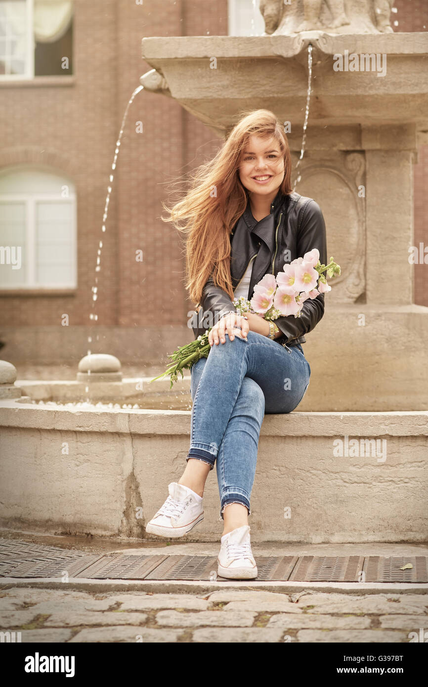 happy woman with flowers near fountain smiling Stock Photo