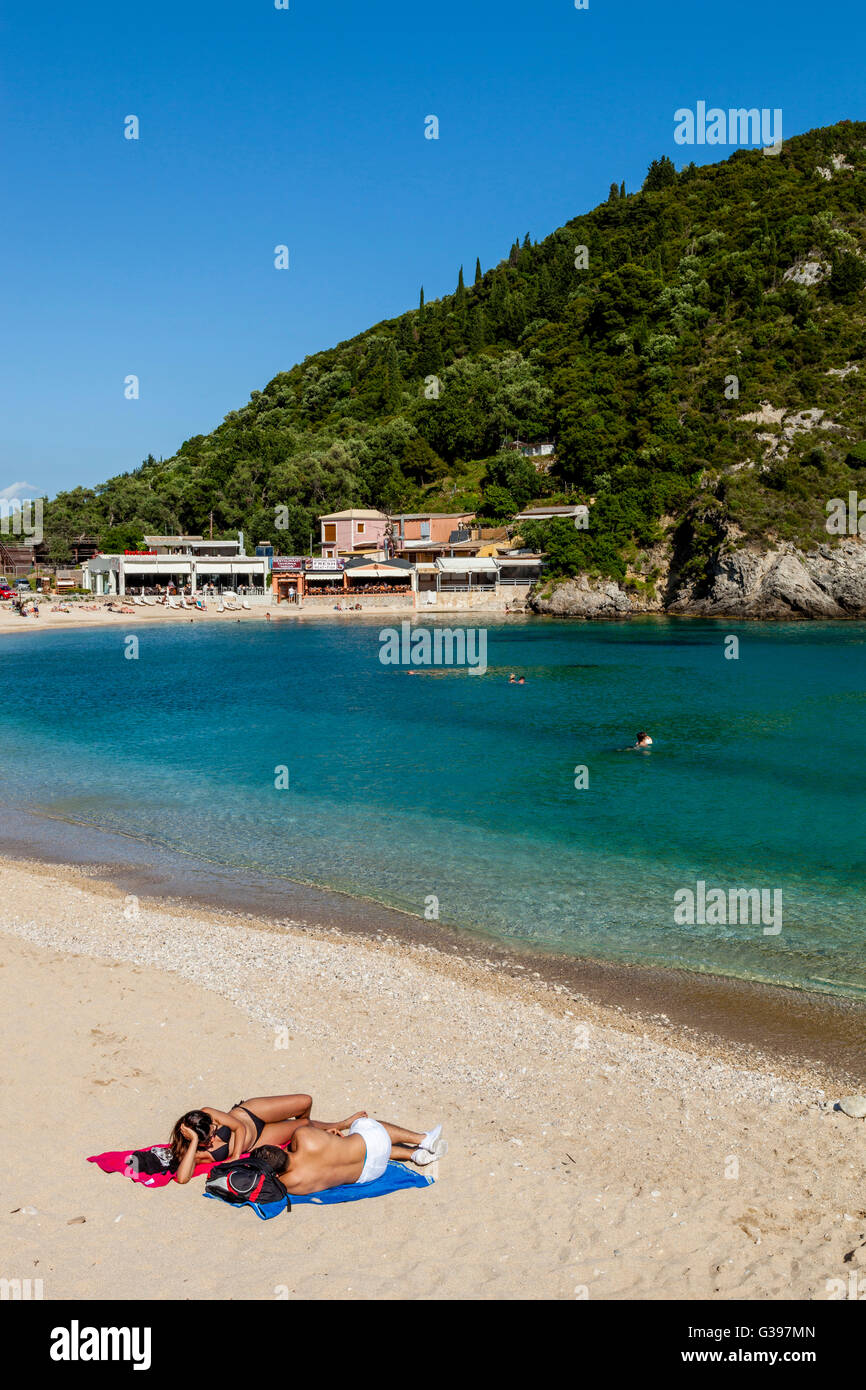 A Young Couple Sunbathing On The Beach At Paleokastritsa, Corfu Island, Greece Stock Photo