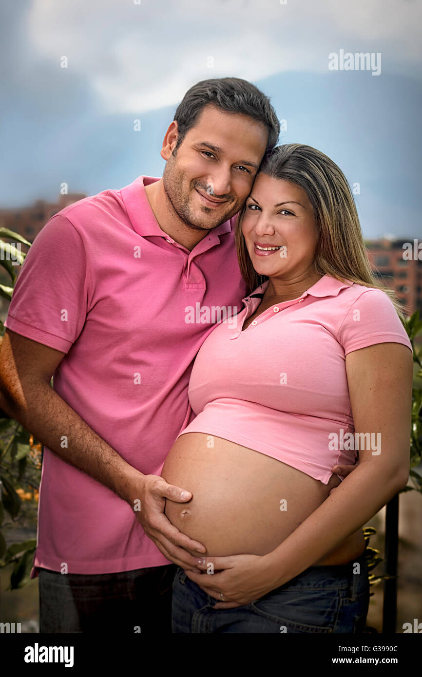 Portrait of a happy young couple expecting a new baby, hugging outdoors. Husband is caressing wife's belly. Outdoors. Stock Photo