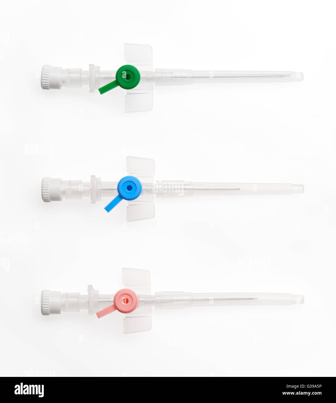 Blue, pink and green plastic catheters with needles closed by protective caps isolated on white background. Stock Photo