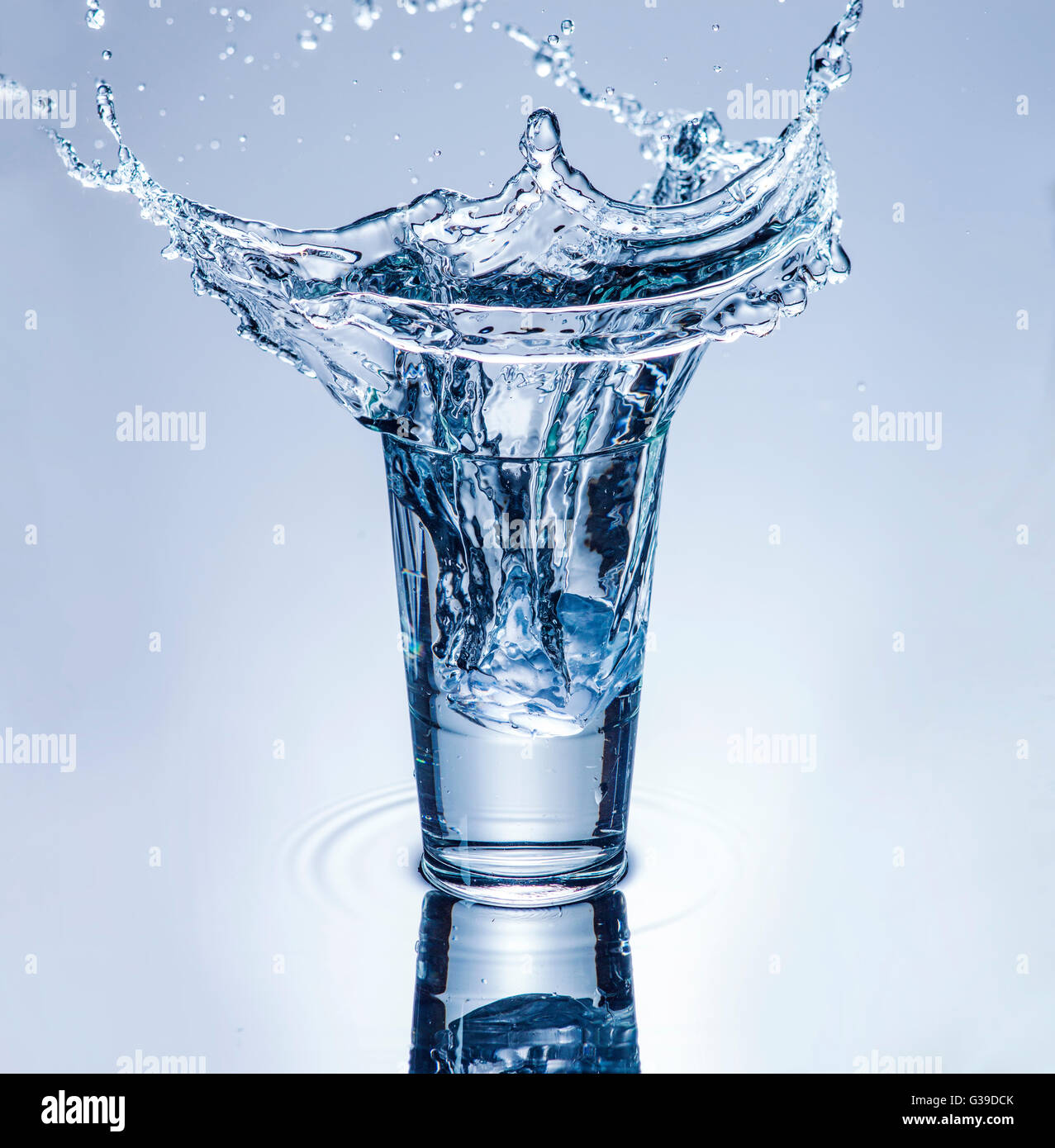 icecube splashing into a glass of water. Stock Photo