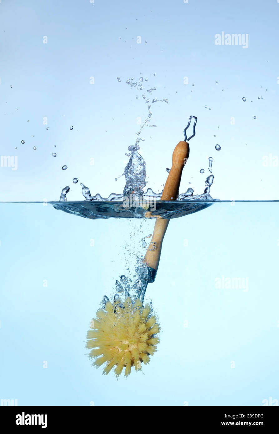 dish brush falling and splashing into water. Stock Photo
