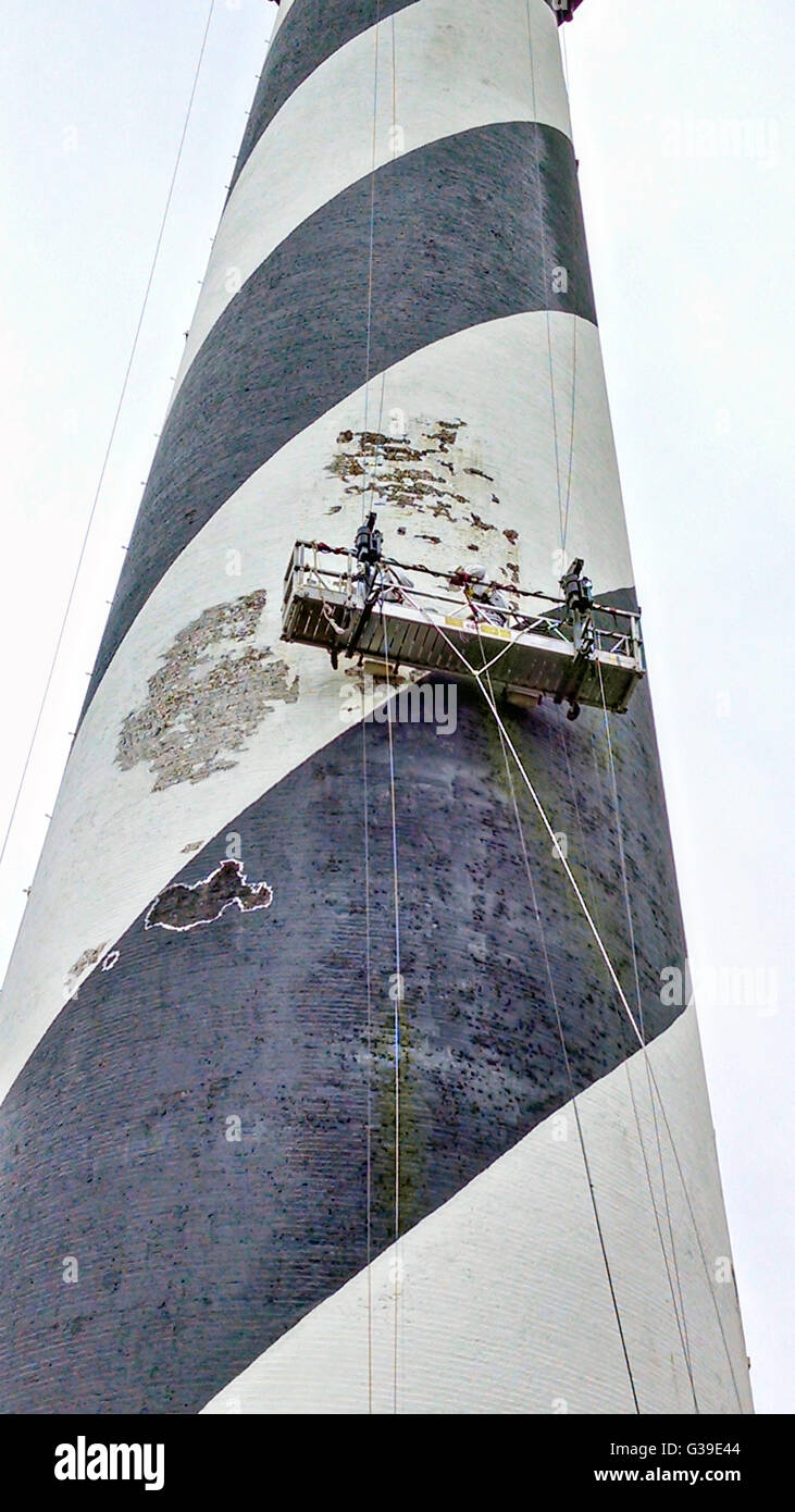 Workers remove flaking paint in preparation for repainting the white spiral stripe on Cape Hatteras lighthouse at Cape Hatteras National Seashore April 28, 2014 in Buxton, North Carolina. Stock Photo