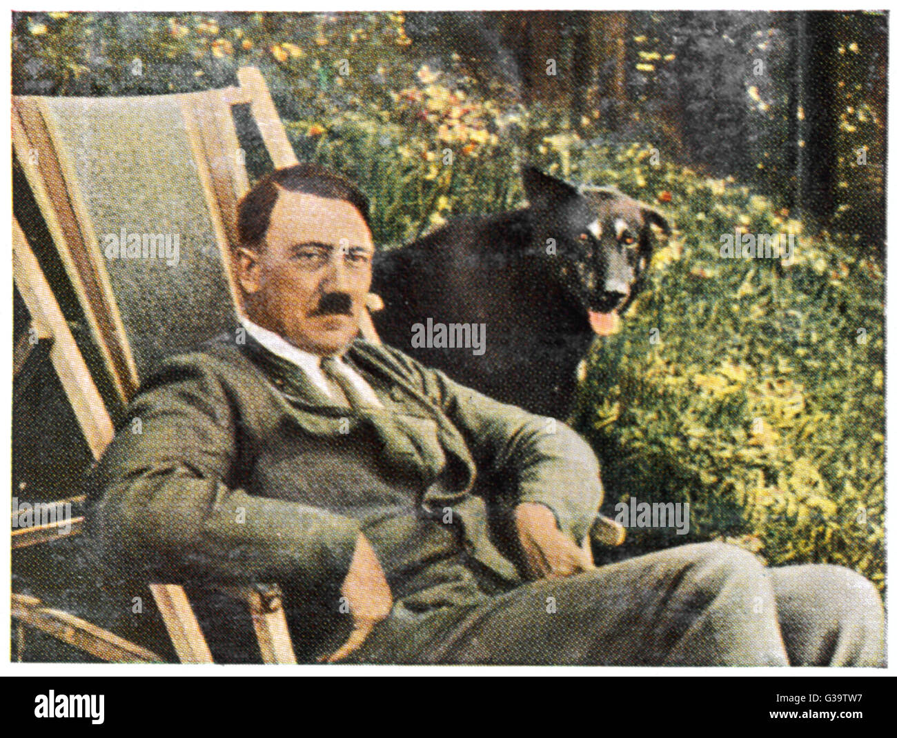 ADOLF HITLER (1889-1945), relaxing in a deckchair at Berchtesgaden, with a black dog at his side.     Date: circa 1933 Stock Photo