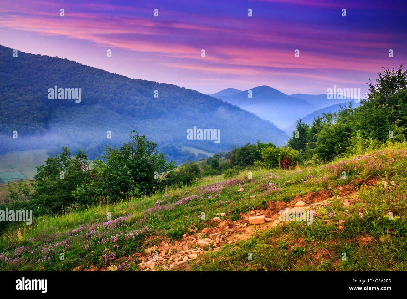 view of the mountains in the fog in the morning standing on a hillside Stock Photo