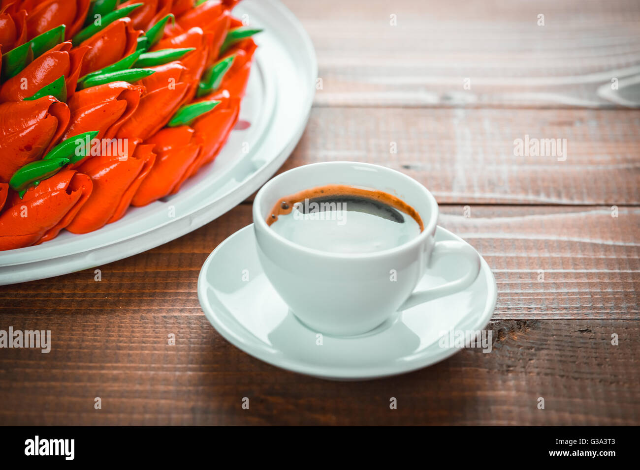 Beautiful background with a Cup of hot coffee with foam and a birthday cake with flowers on wooden background Stock Photo