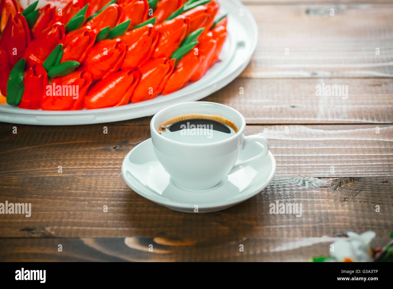 Beautiful background with a Cup of hot coffee with foam and a birthday cake with flowers on wooden background Stock Photo