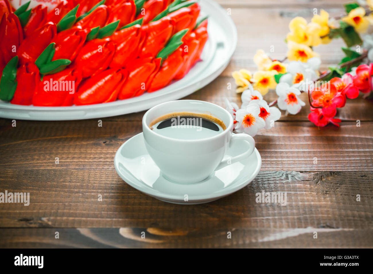 Beautiful background with a Cup of hot coffee with foam and a birthday cake with flowers on wooden background Stock Photo