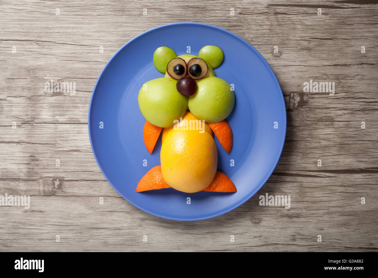 Funny hamster made of fruits on plate and wooden background Stock Photo