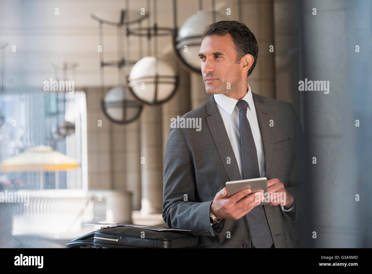 Corporate businessman with digital tablet looking away Stock Photo