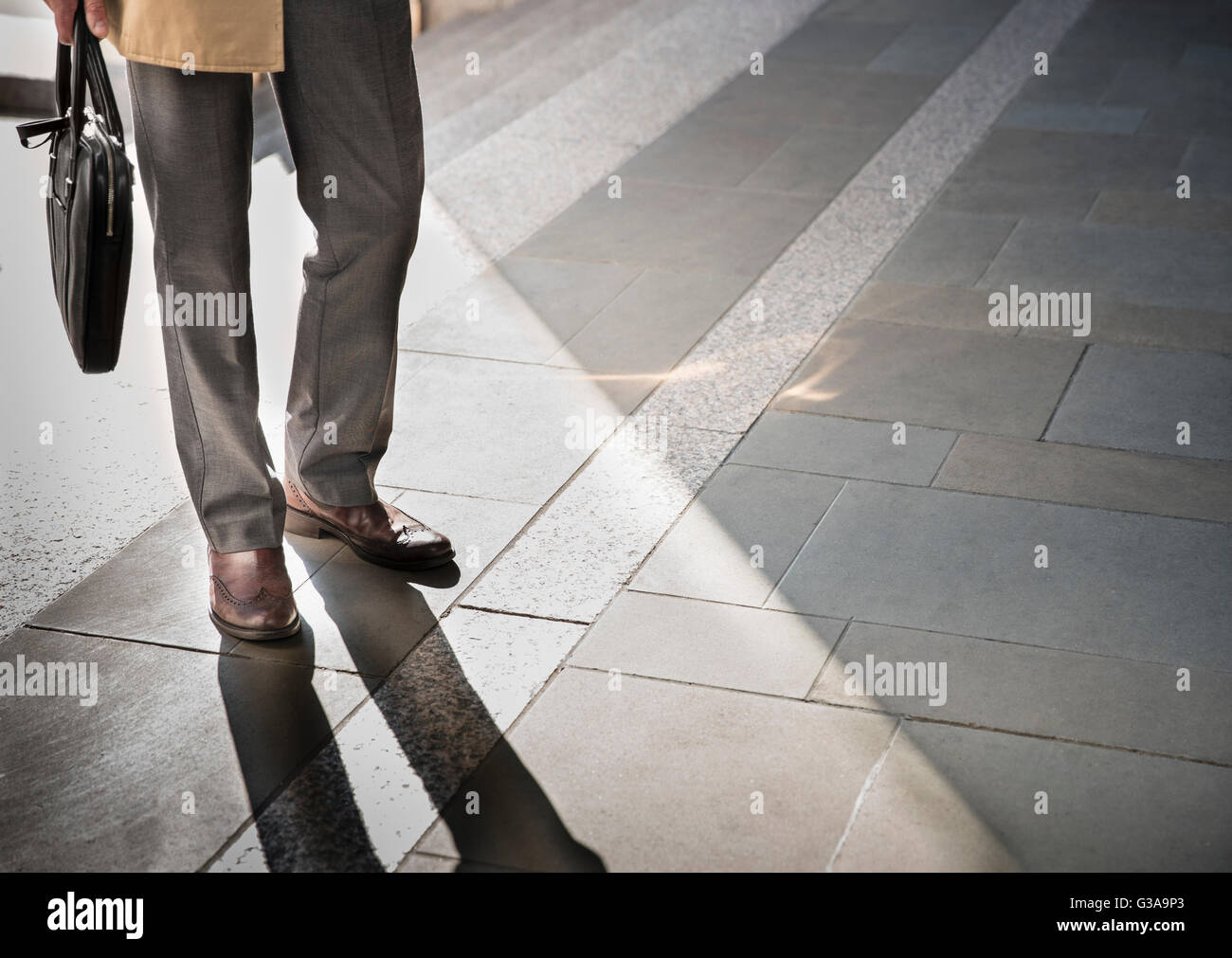 Corporate businessman standing on sunny pavement Stock Photo