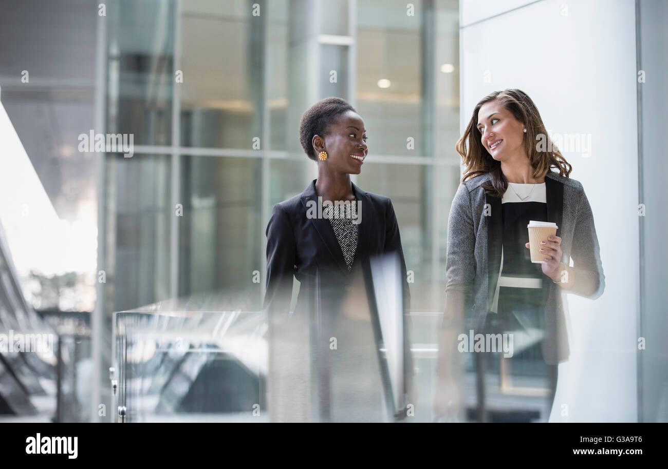 Corporate businesswomen with coffee talking and walking Stock Photo