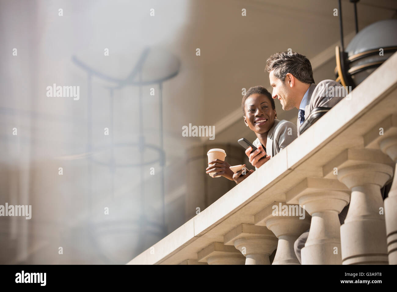 Corporate businessman and businesswoman drinking coffee at railing Stock Photo