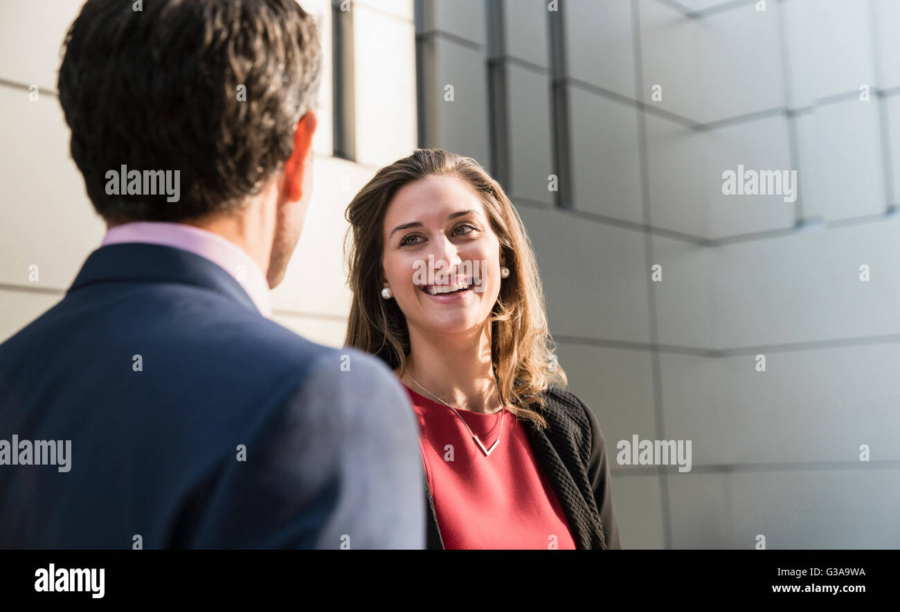 Corporate businesswoman smiling and talking to businessman Stock Photo