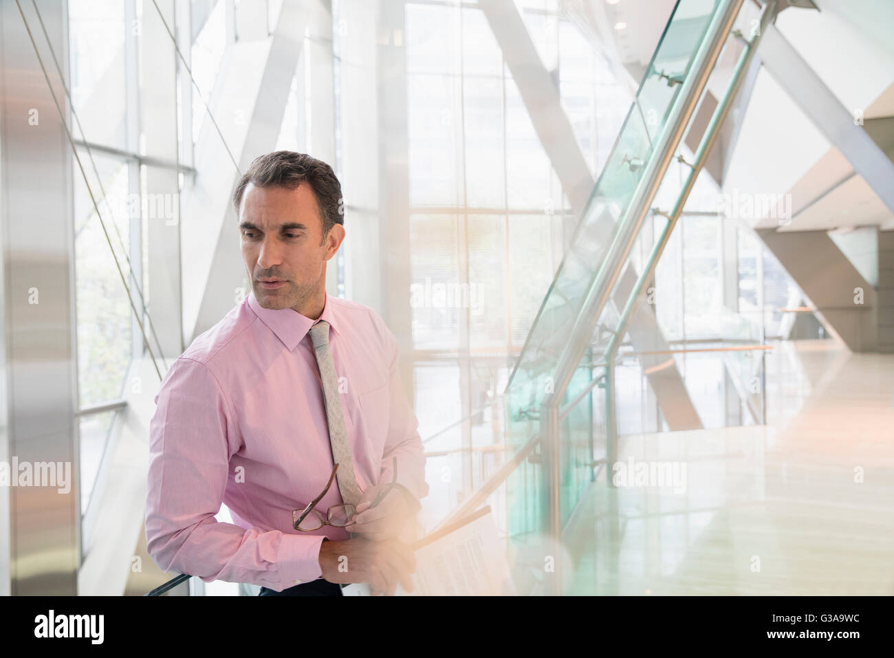 Pensive corporate businessman looking down in modern office lobby Stock Photo