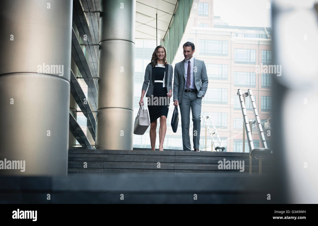 Corporate businessman and businesswoman descending stairs outdoors Stock Photo