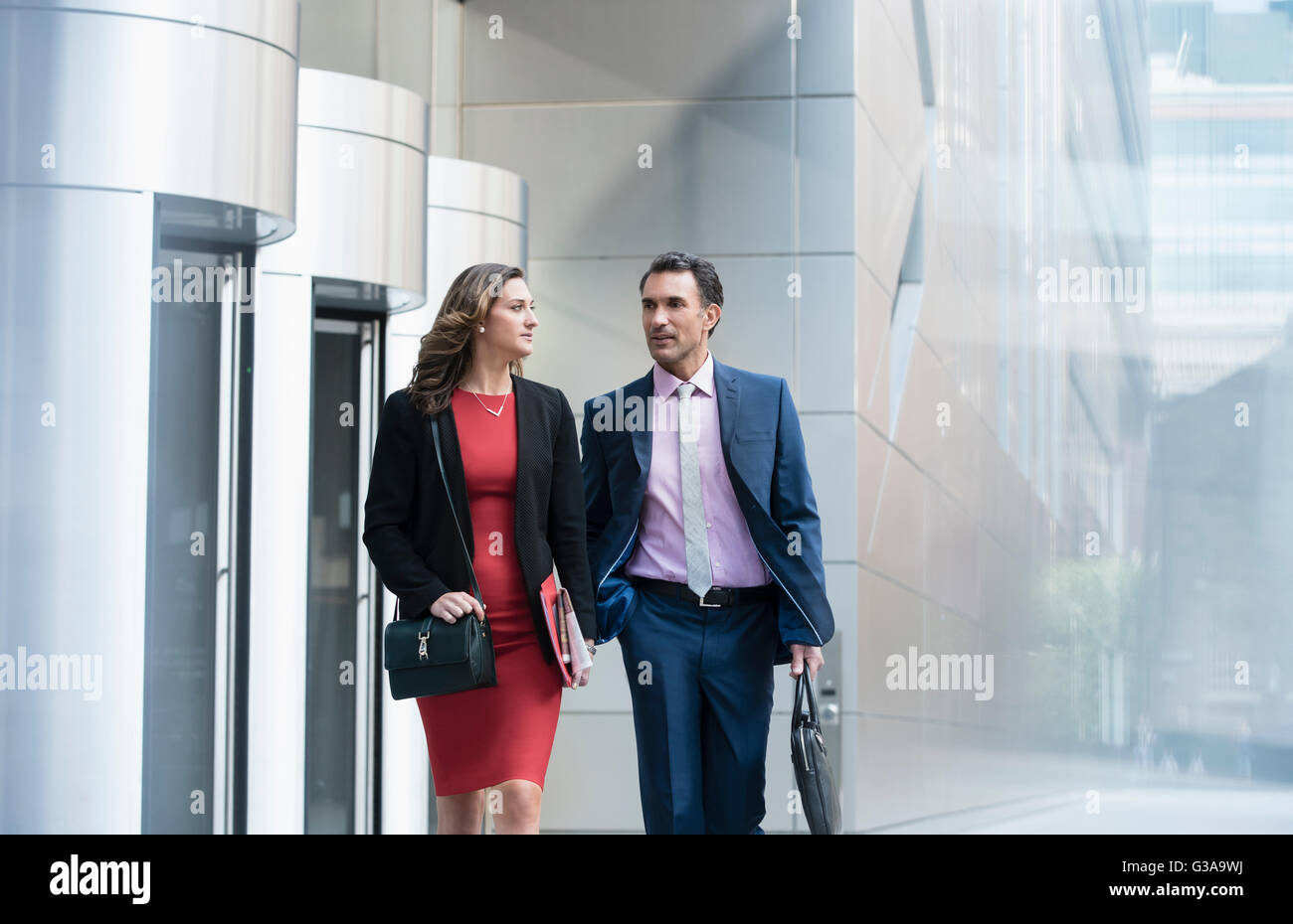 Corporate businessman and businesswoman walking and talking outside building Stock Photo