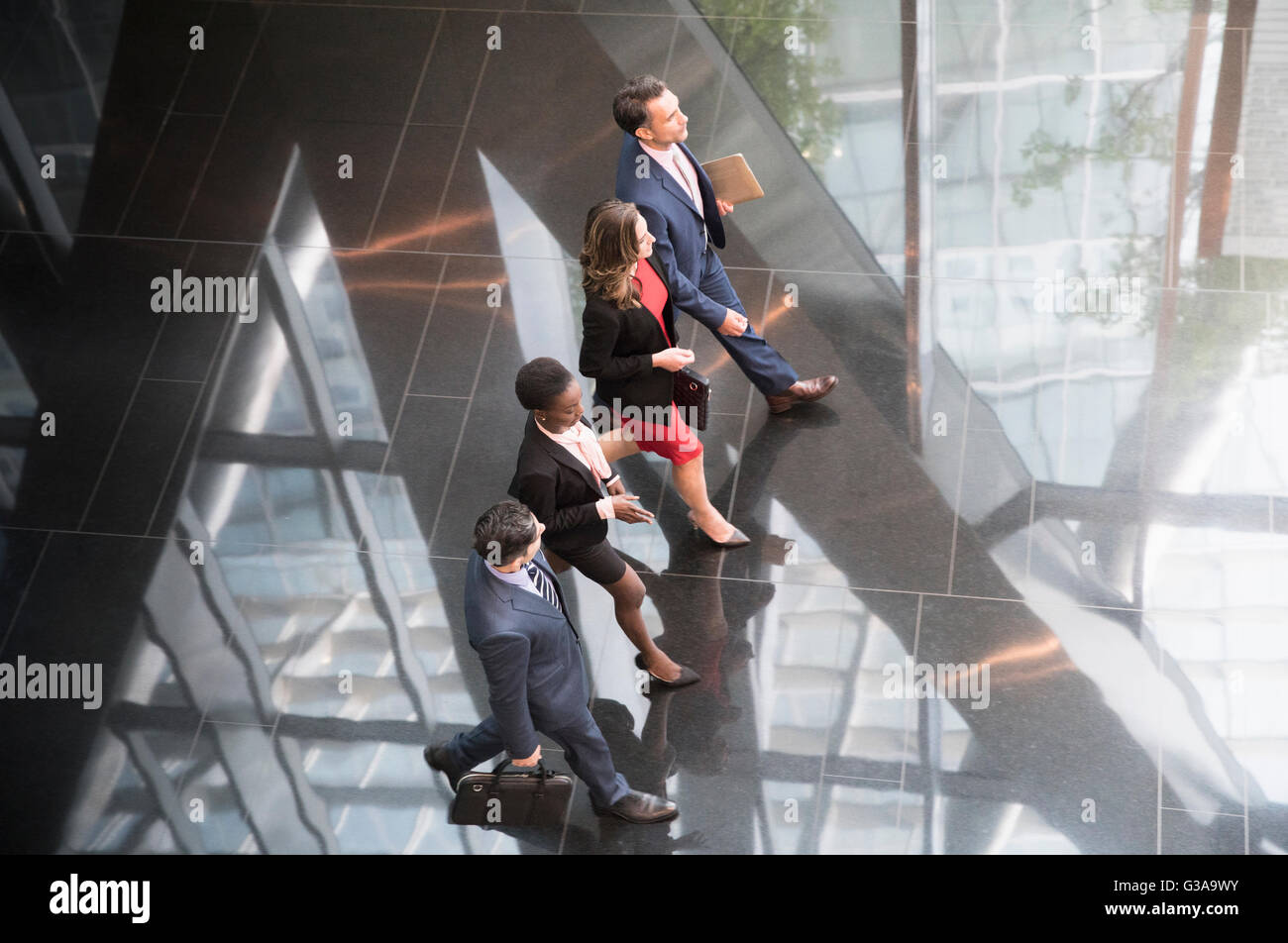 Corporate business people walking in a row in modern office lobby Stock Photo