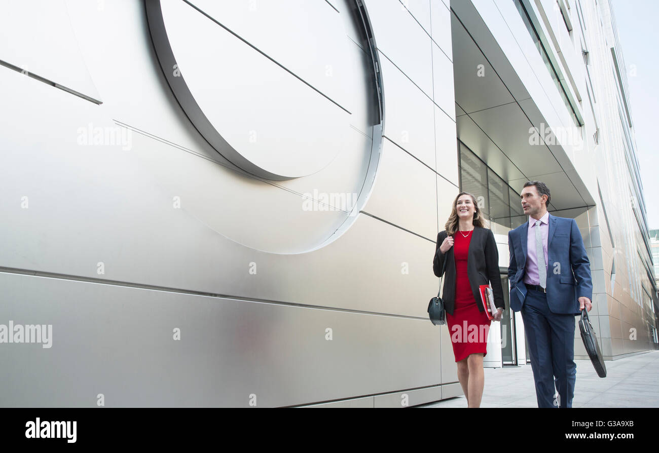 Corporate businessman and businesswoman walking outside modern building Stock Photo