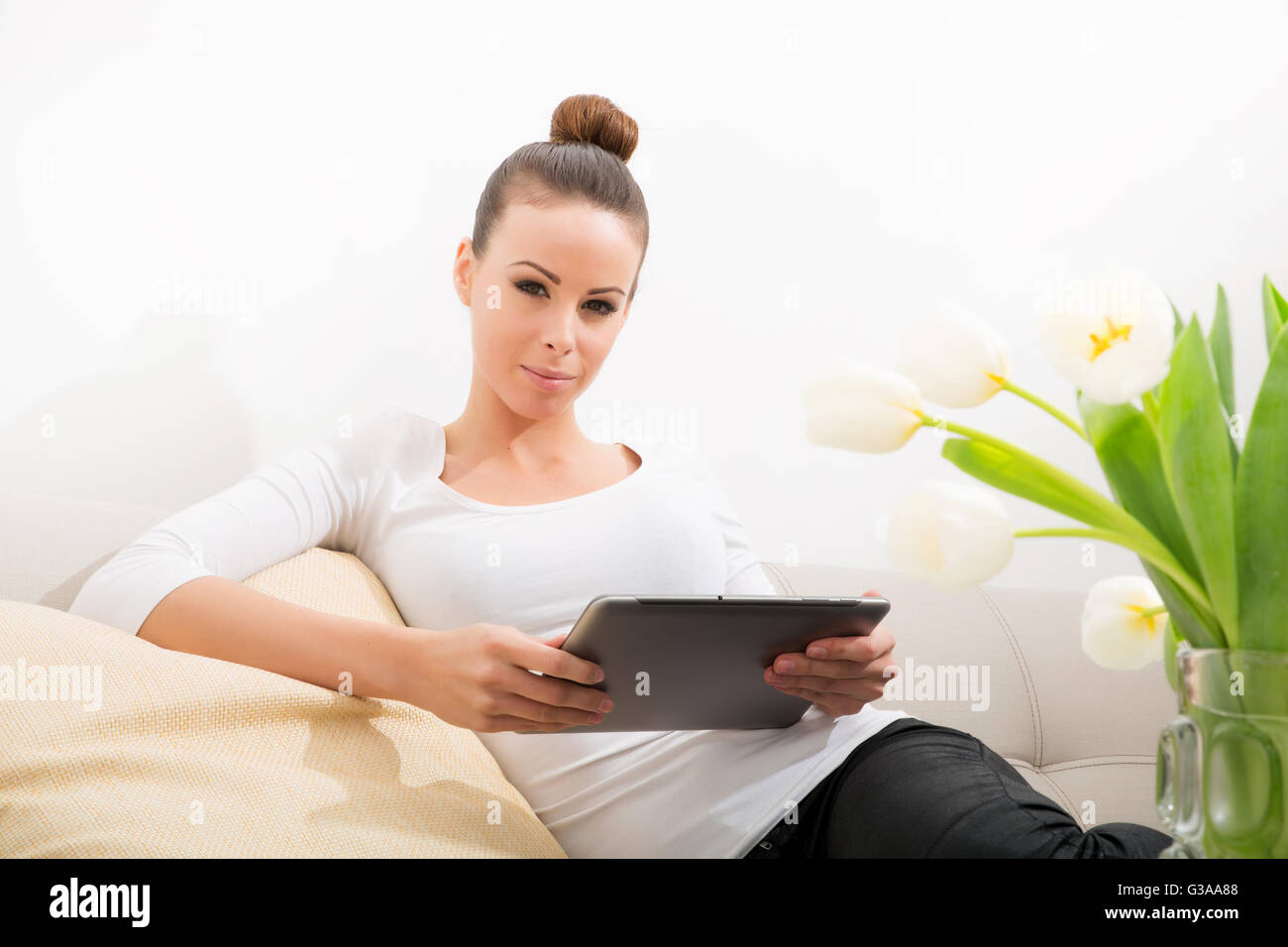 A young woman sitting on the sofa holding a tablet Stock Photo - Alamy