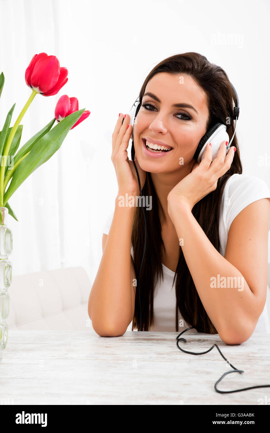 Portrait of a young beautiful woman listening to music with headphones ...