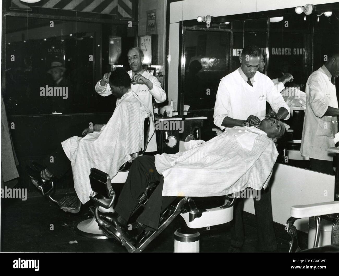 Big-city African-American barbershop proving shaves and haircuts for clientele. Stock Photo