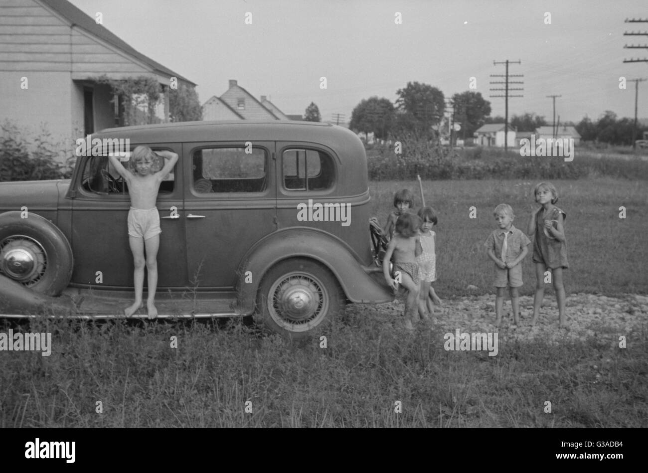 Children playing on a car in 1930s America Stock Photo