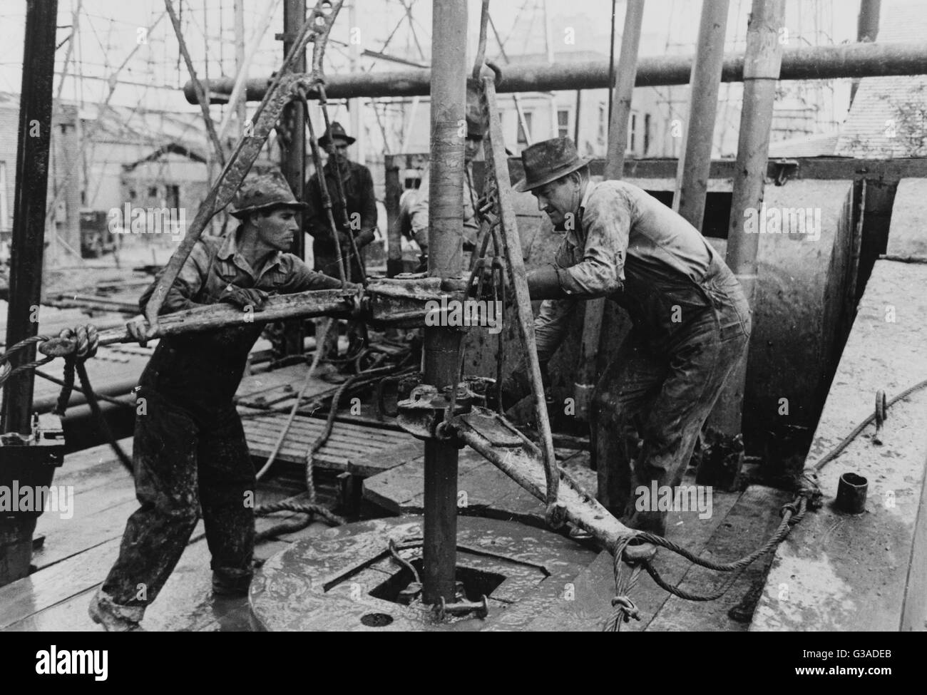 Oil roughnecks screwing one piece of drill pipe to another piece by