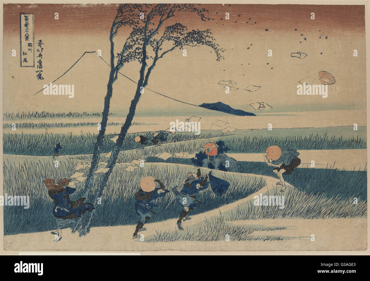 Sunshu ejiri. Print shows several wayfarers struggling against a strong wind that is blowing away hats and papers; Mount Fuji in the background. Date 1832 or 1833. Stock Photo