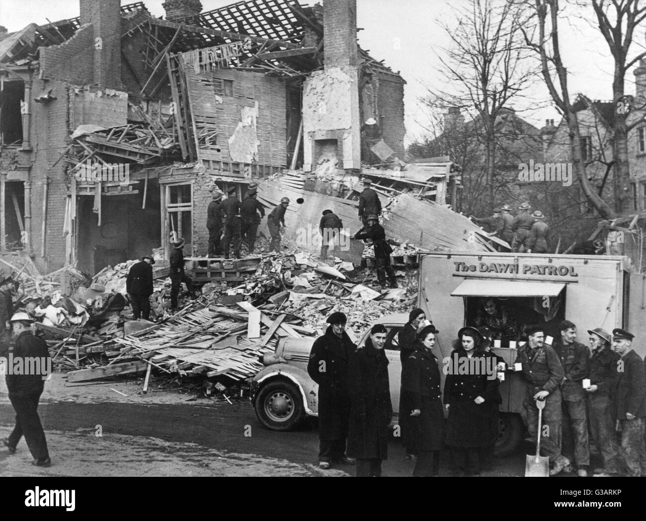 Blitz in London -- aftermath of bombing, with some people sorting through the rubble and others stopping for a refreshment break.      Date: 1940s Stock Photo