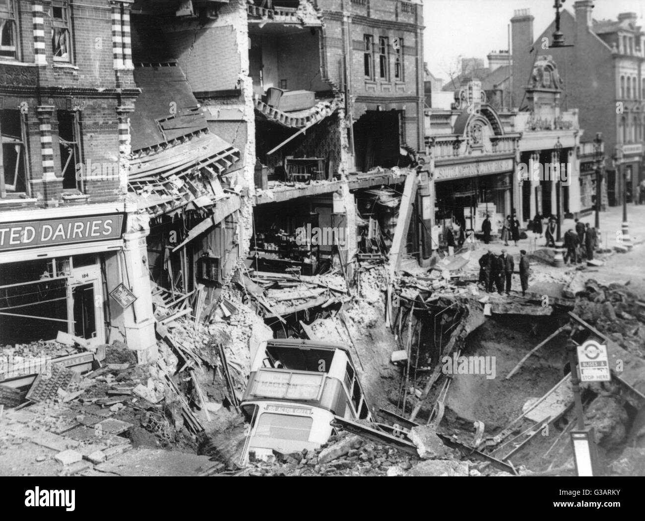Blitz in London -- aftermath of bombing, with a row of ruined buildings, and a route 88 bus for Acton Green in a large crater in the road.      Date: 1940s Stock Photo