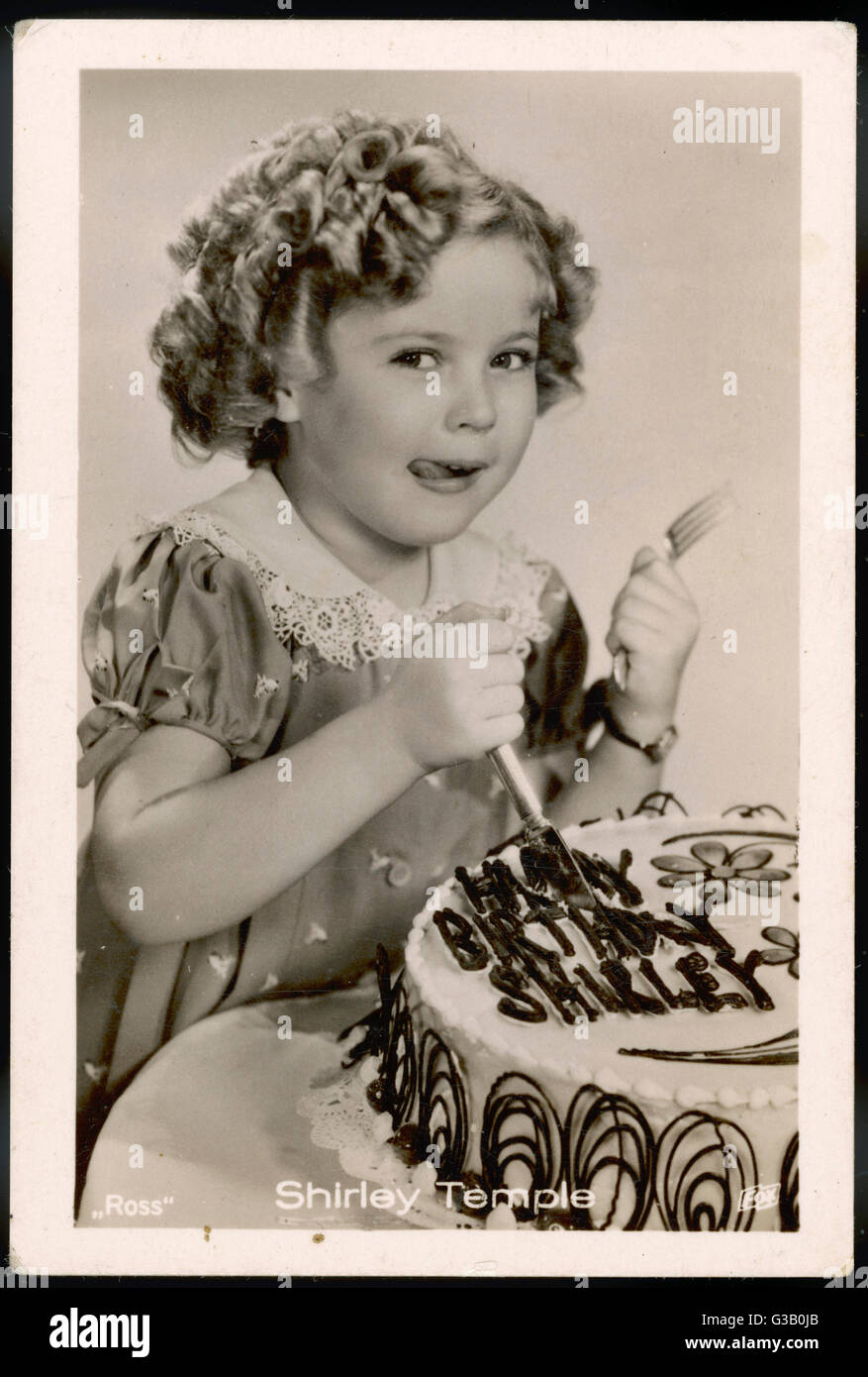 SHIRLEY TEMPLE  (1928 -2014), American child star of the 1930s, tucking into her birthday cake      Date: 1930s Stock Photo