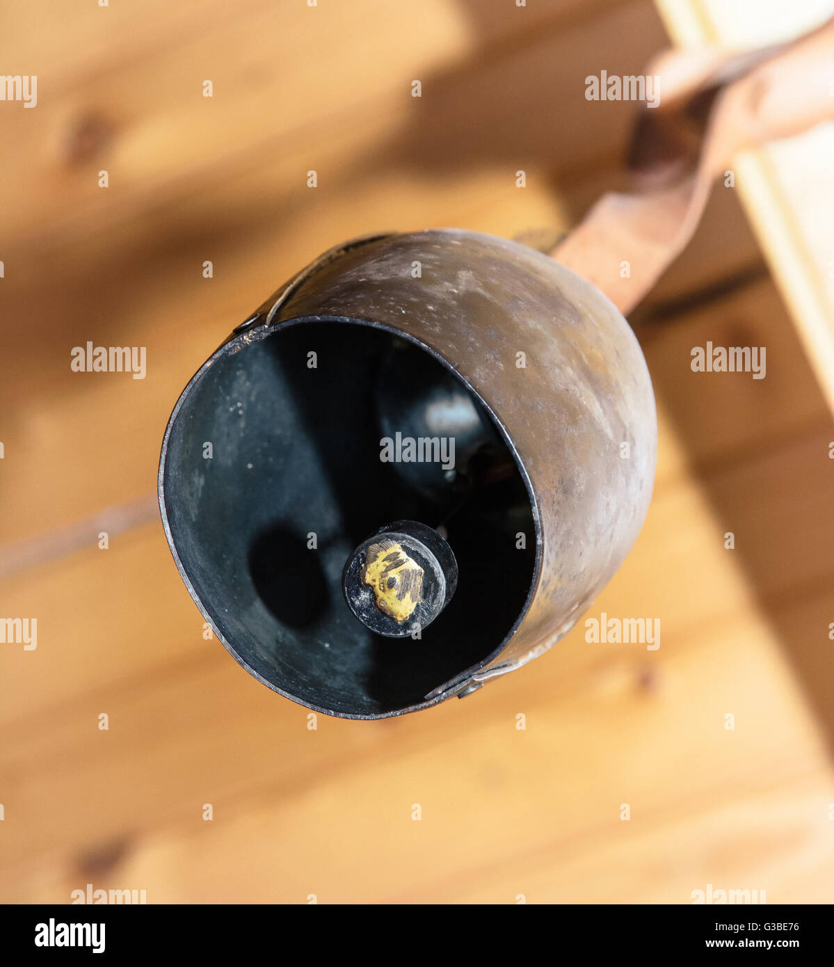 Symbolic cowbell hanging on the wooden beam. Metal bell. Symbol of