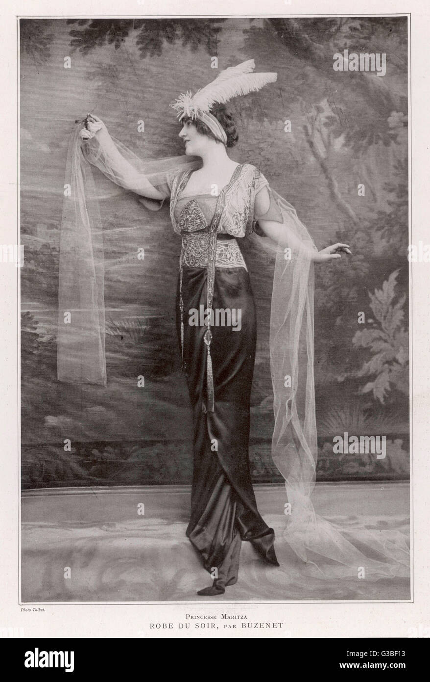 Exotic gown witih Chinese  style tassels, a narrow draped  satin skirt with train worn  with an embroidered lace,  square necked bodice with  decorative cut under-sleeves.     Date: 1913 Stock Photo