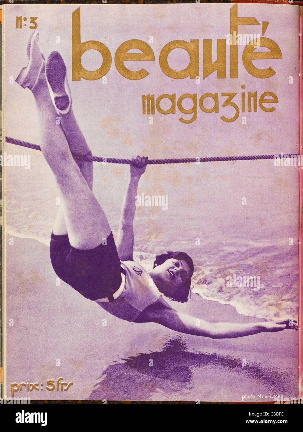 A sporty young lady in shorts  hangs upside down from a rope  above the sea, presumably to  demonstrate her athletic  ability.      Date: 1929 Stock Photo