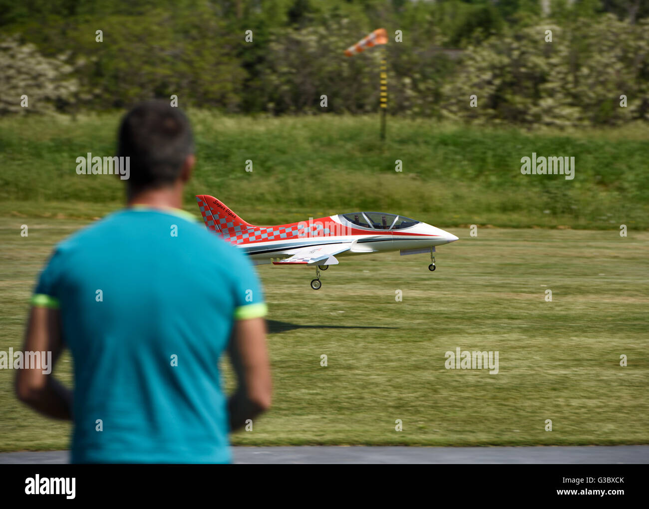 Hobbyist landing a radio controlled jet scale model with electric engine on grass runway Stock Photo