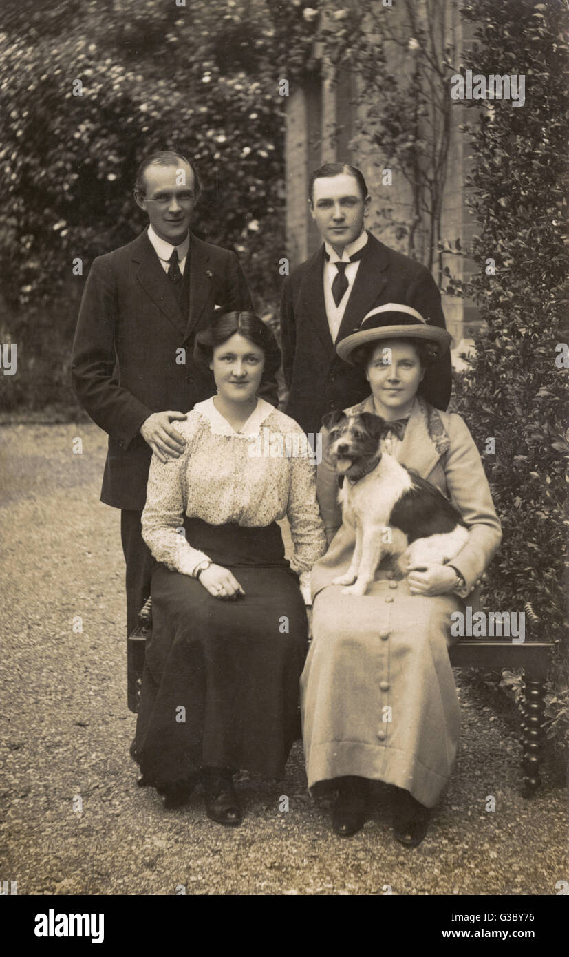 Two men, two women and dog in garden Stock Photo
