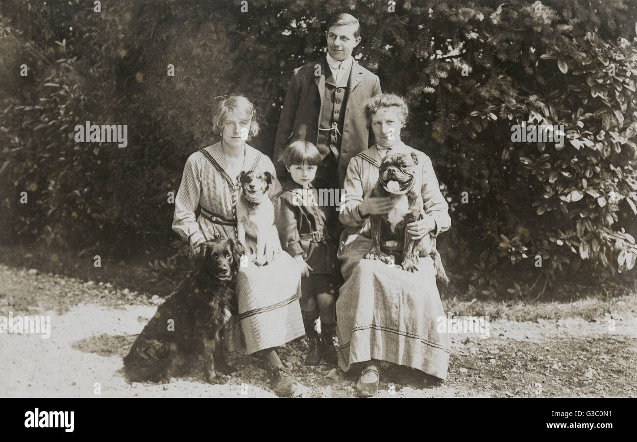 Four people and three dogs in a garden Stock Photo - Alamy