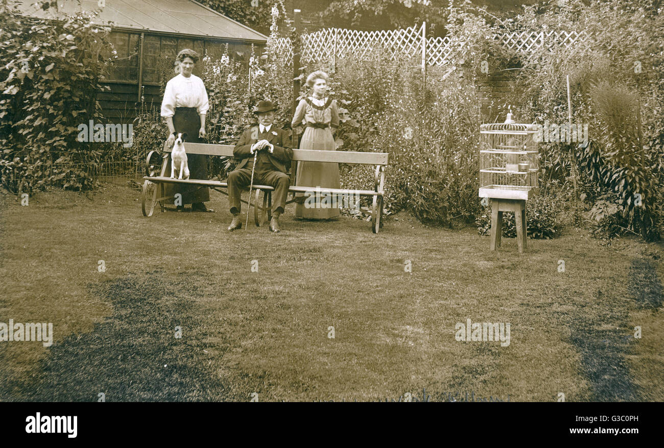 Three people with a dog in a garden Stock Photo - Alamy