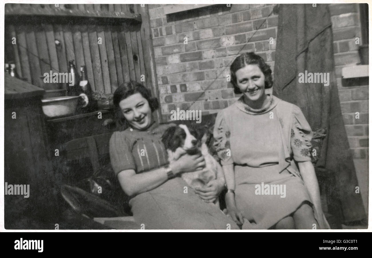 Two women with a dog in a back garden Stock Photo - Alamy