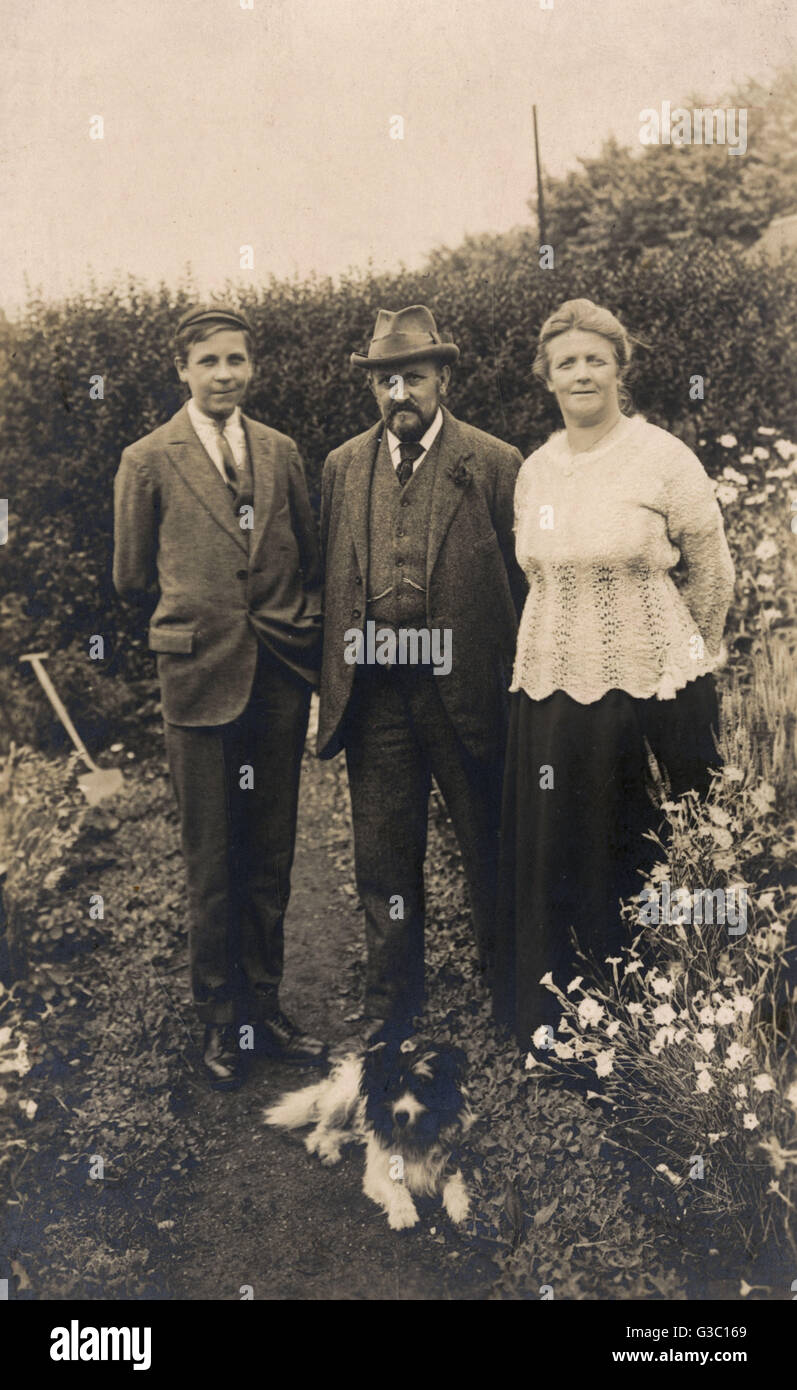 Family of three with a dog in a garden Stock Photo - Alamy